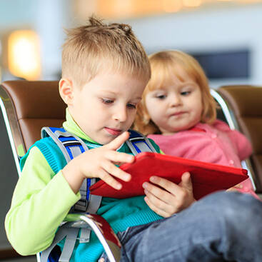 children watching something on a red tablet while waiting at the airport