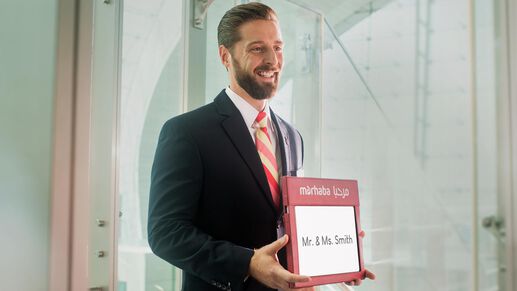 male marhaba representative holding a name sign with Mr. & Ms. Smith written on it