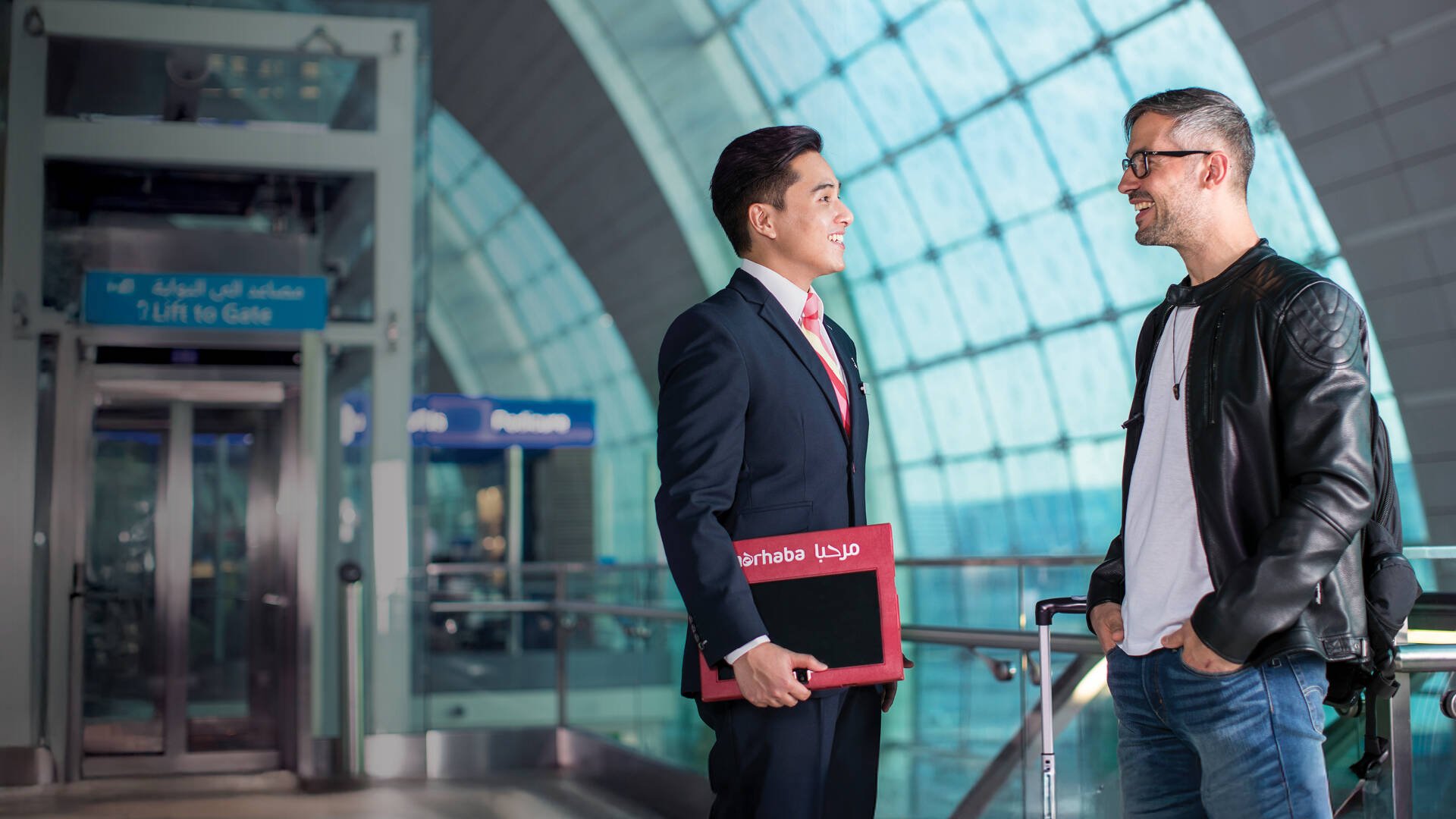 A marhaba team member standing with a passenger and smiling